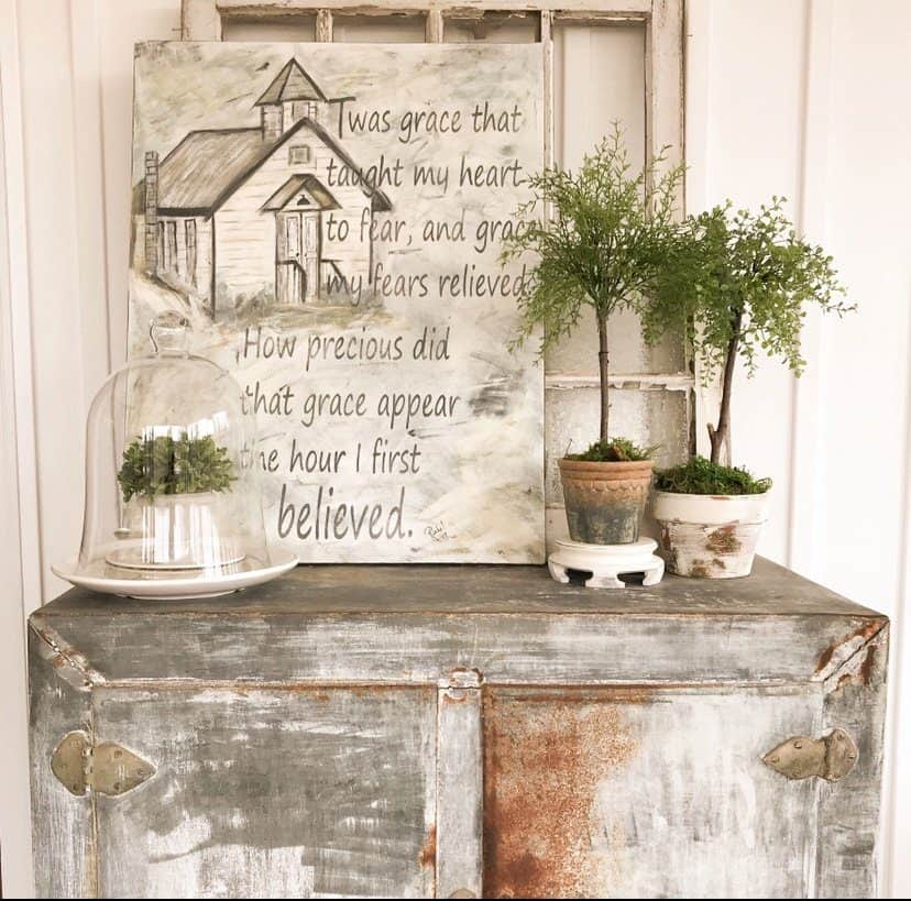 Aged Terra Cotta Pots filled with faux topiaries and a old church painting on a metal vintage ice box.