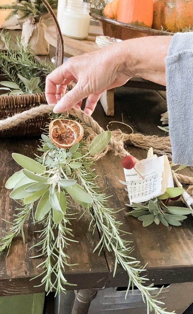 Use Hot glue to attach dried fruit to the fresh herbs, rosemary and sage herbs with dried orange slices.  
