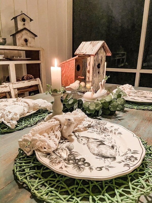 Screened in porch Easter table with black and white bunny plates, bunny napkin rings and green placemats