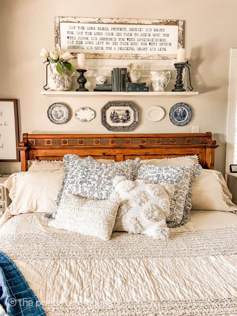 Easy farmhouse style bedroom ideas for Spring with ruffled bedding and blue and white florals on pine bed with decorative plates