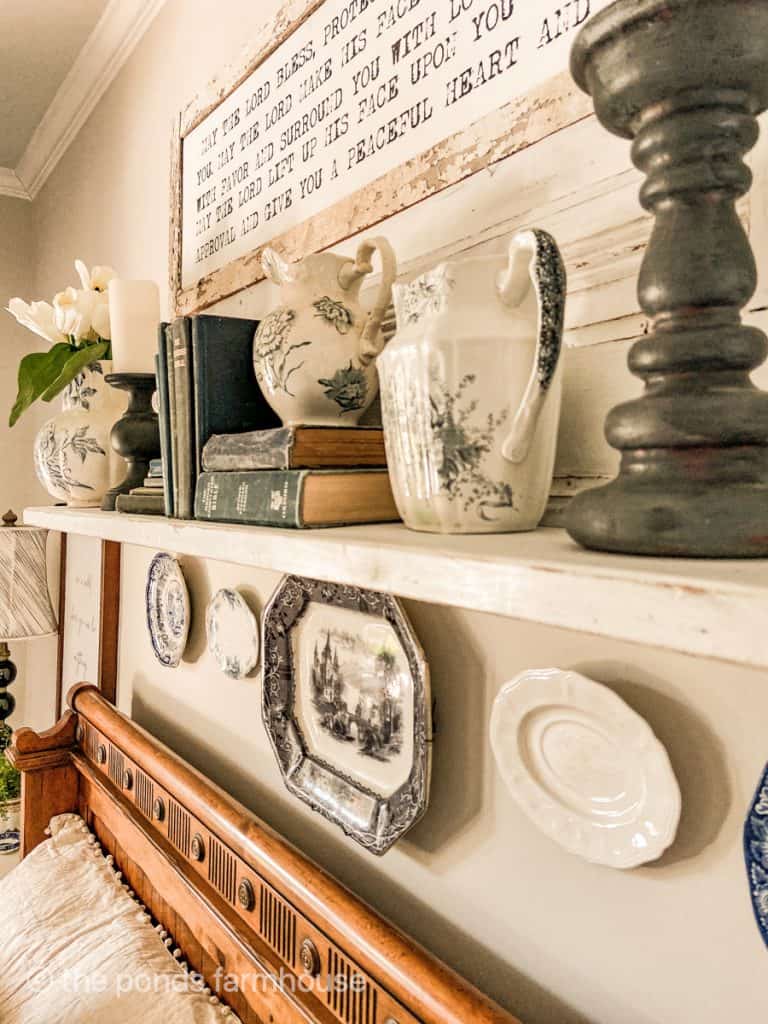 Shelf above bed is repurposed mantel with blue and white vintage dishes and pitchers.