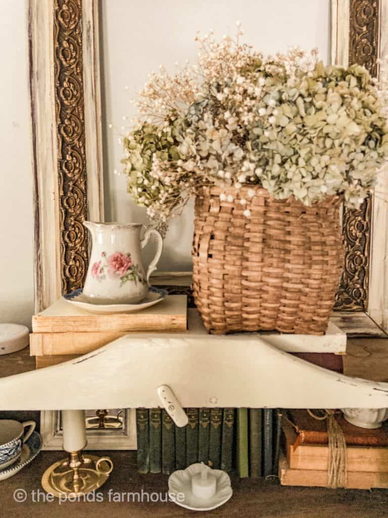 wicker basket holds dried flowers on cabinet top.  