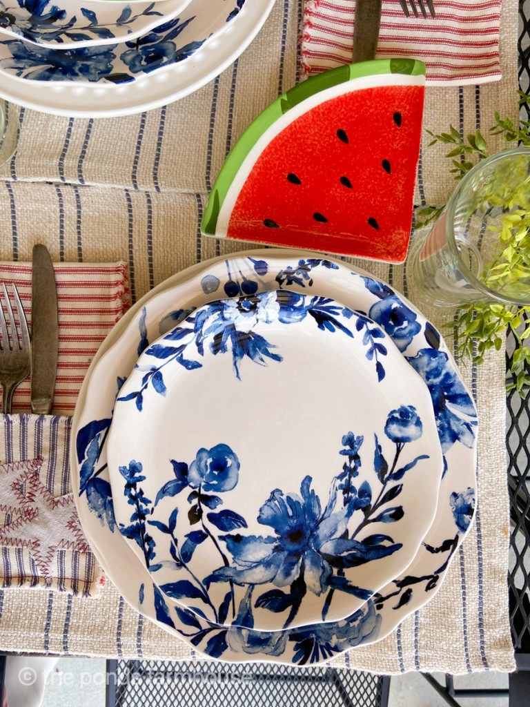 Blue and white dishes on striped placemat.  Watermelon slice plate for a festive Fourth of July Tablescape.