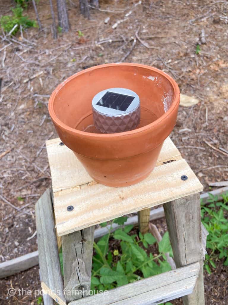 Add solar light to a clay terra cotta pot on top of the standing tower.