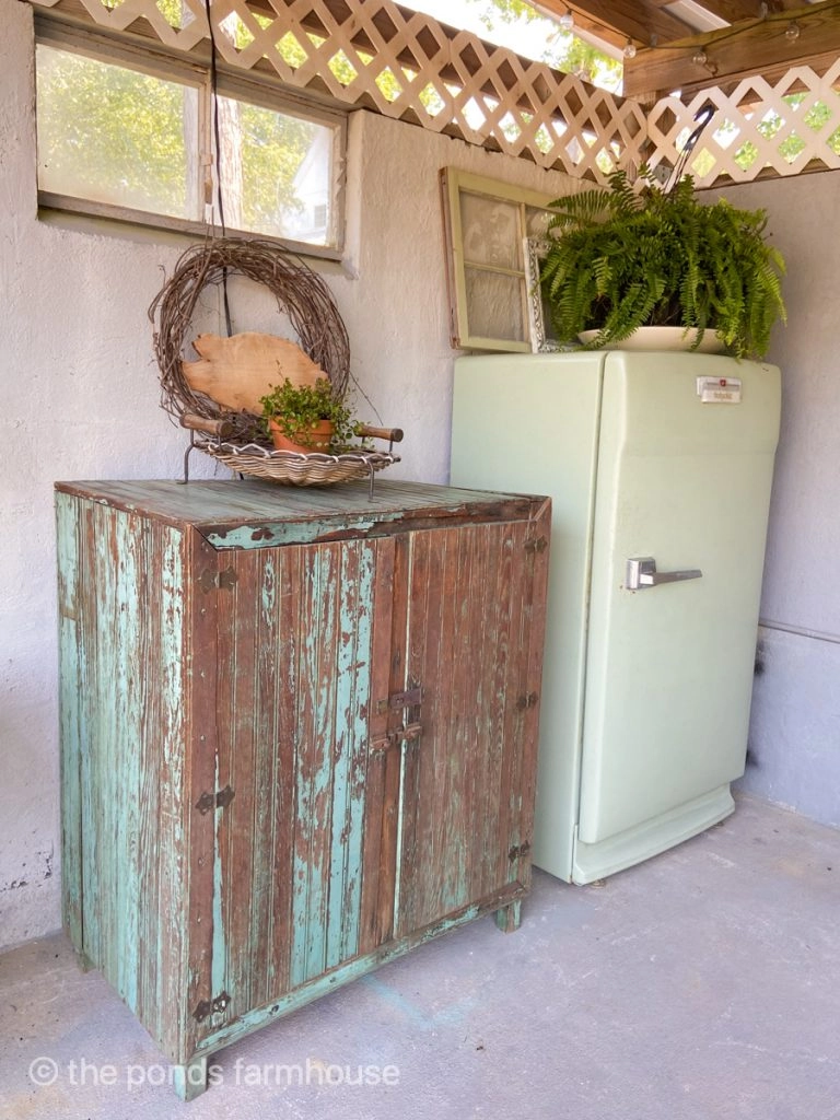Vintage outdoor kitchen decor includes chippy cabinet and old vintage refrigerator.  