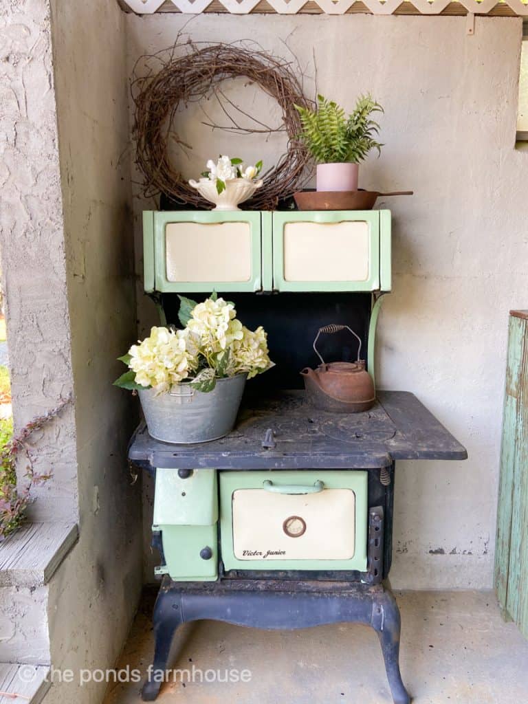 Antique wood cook stove in green and black decorate the outdoor kitchen.