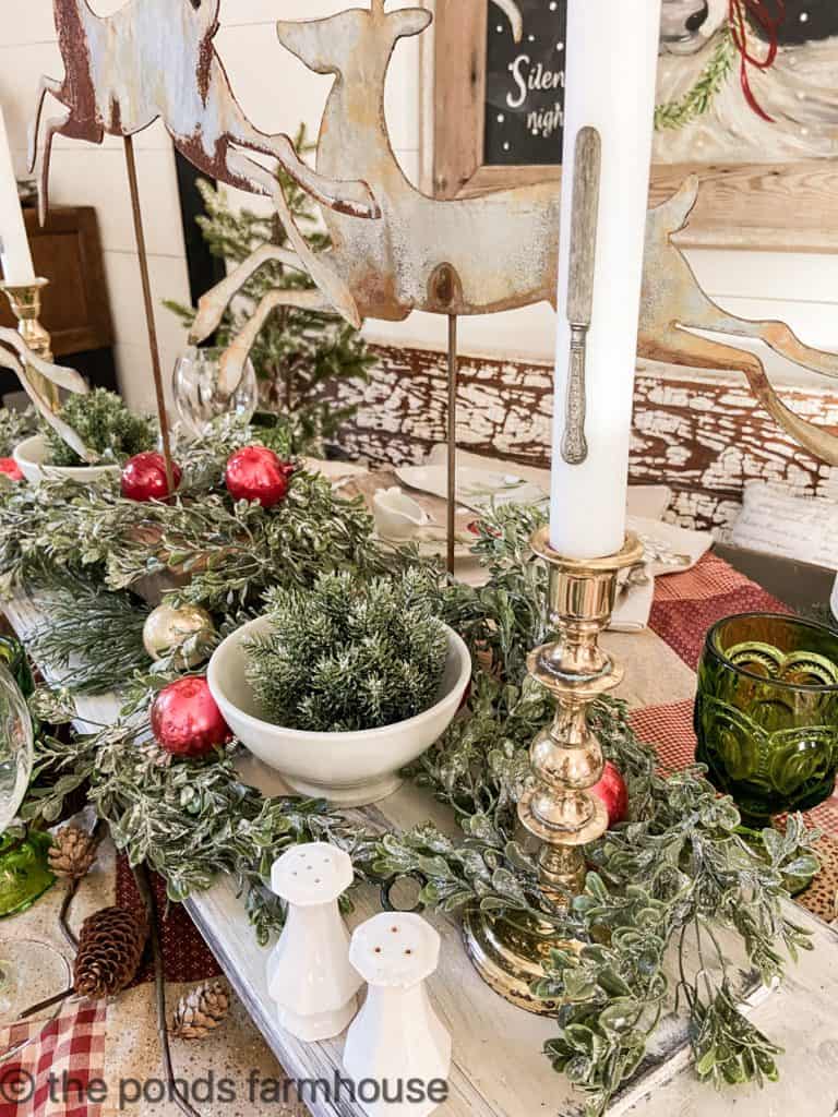 Close up of Creative Christmas Table Decorations with Lucid Candles and greenery.