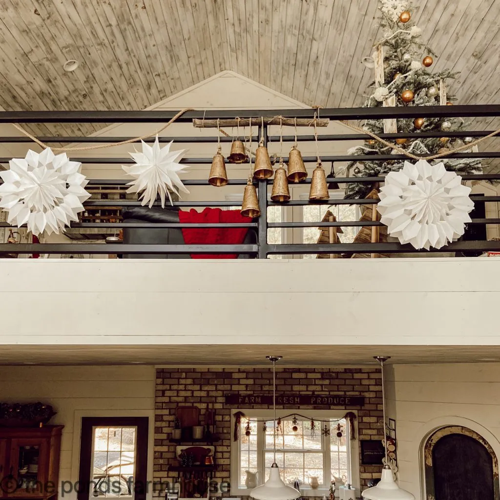 Loft view of Christmas Garland made from DIY Paper Bag Snowflakes and Vintage Inspired Brass Bells 