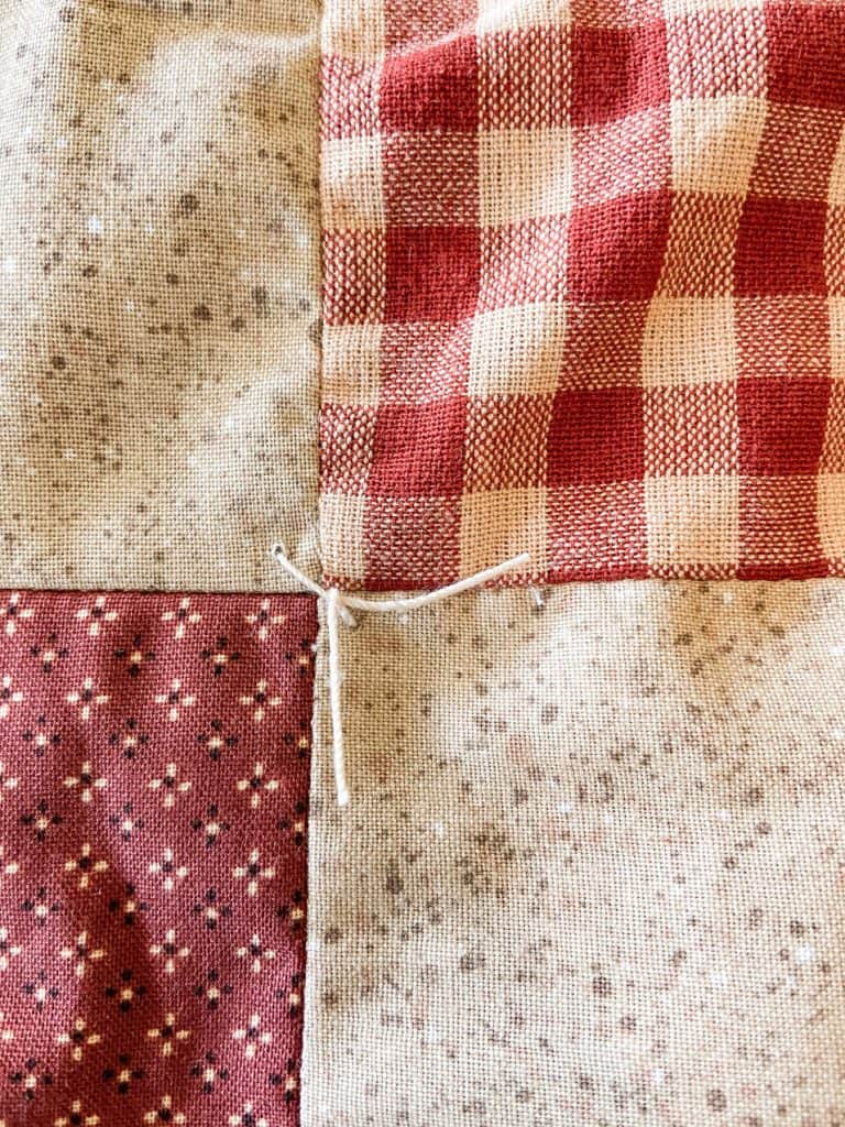 add a stitch to each corner and tie a knot to secure the lining to the top of the quilt.