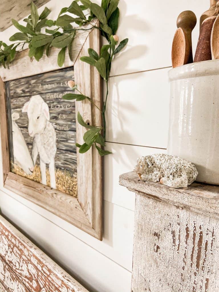 Lamb painting hanging over a bench. Tips on how to hang this art perfectly every time.