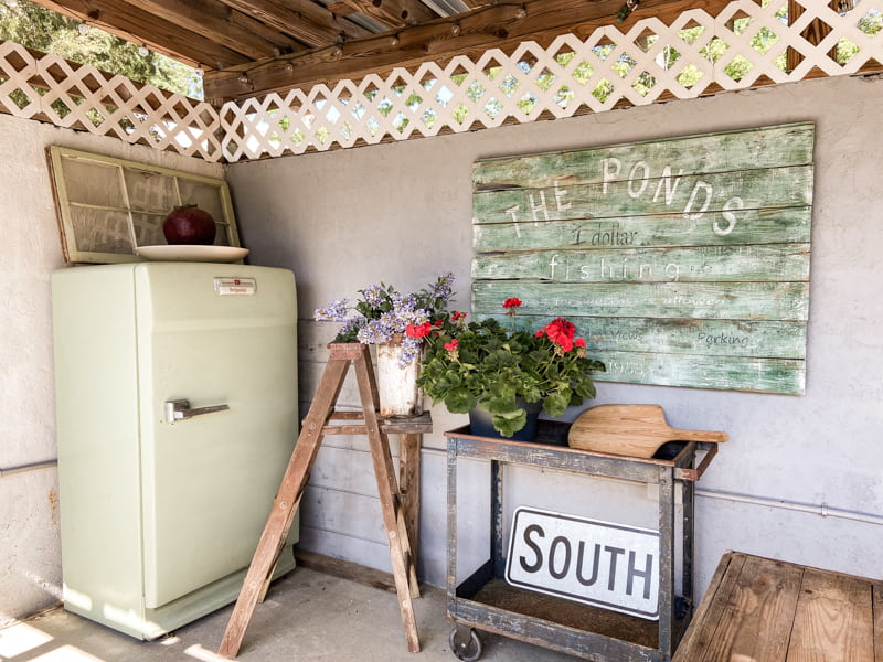 Vintage sign tutorial in outdoor kitchen with vintage ladder and refrigerator in outdoor kitchen