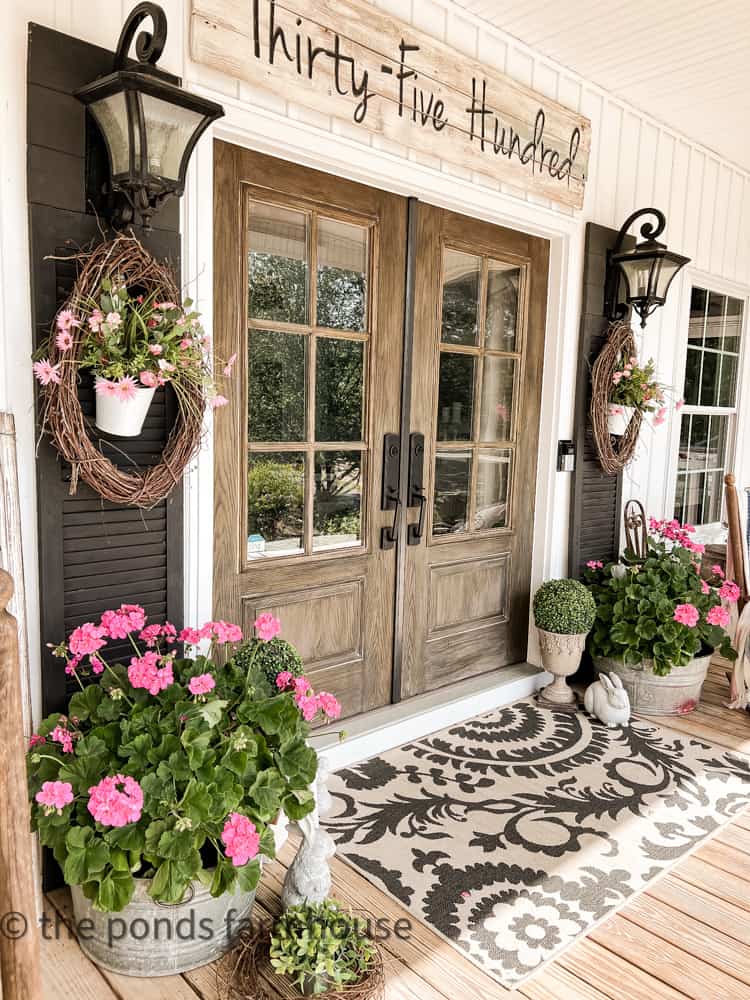 Farmhouse Style porch is filled with geraniums. Galvanized porch planters.