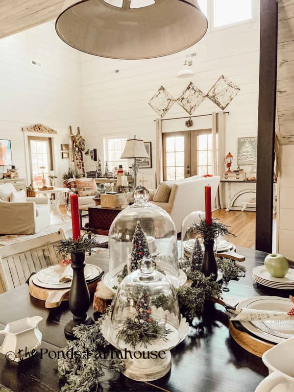 Christmas Past Farmhouse Table with bottle brush trees under cloches with living room view