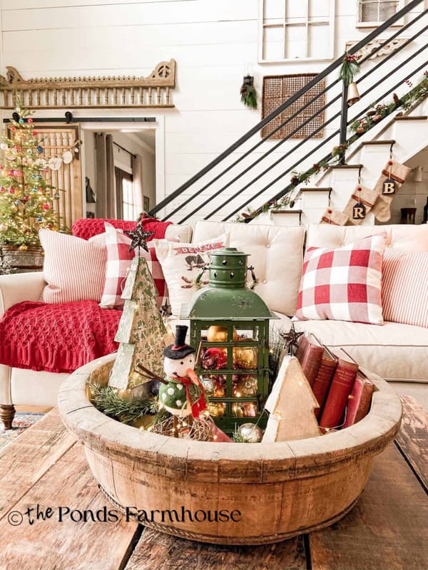 Christmas past living room with wooden bowl coffee table centerpiece and white sofa with red and white decorations