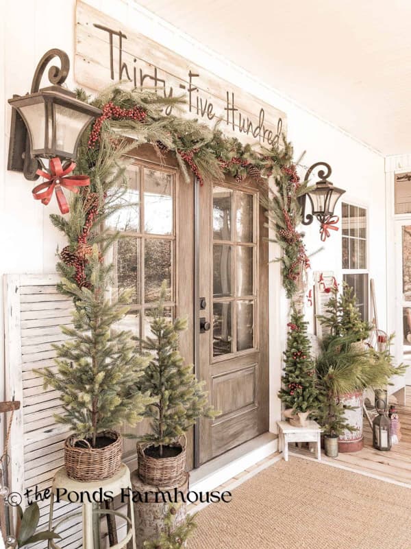 Farmhouse Front Porch Decorated for Christmas Past with mini trees and garlands