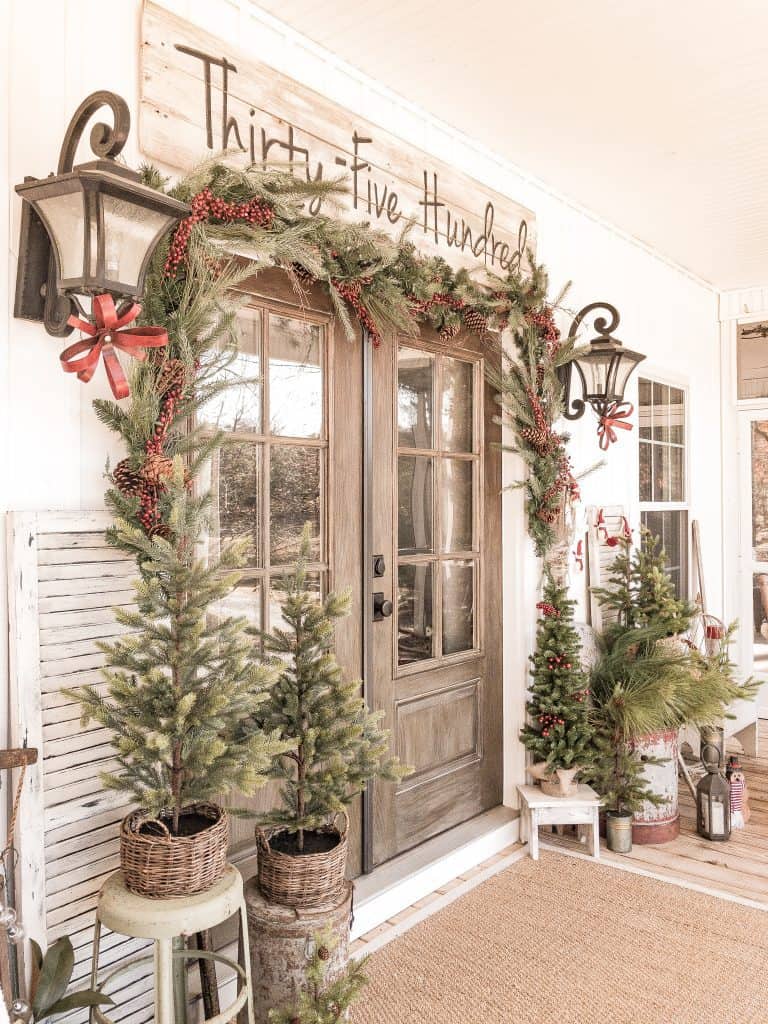 Farmhouse Front Porch Decorated for Christmas with Garland and metal bows