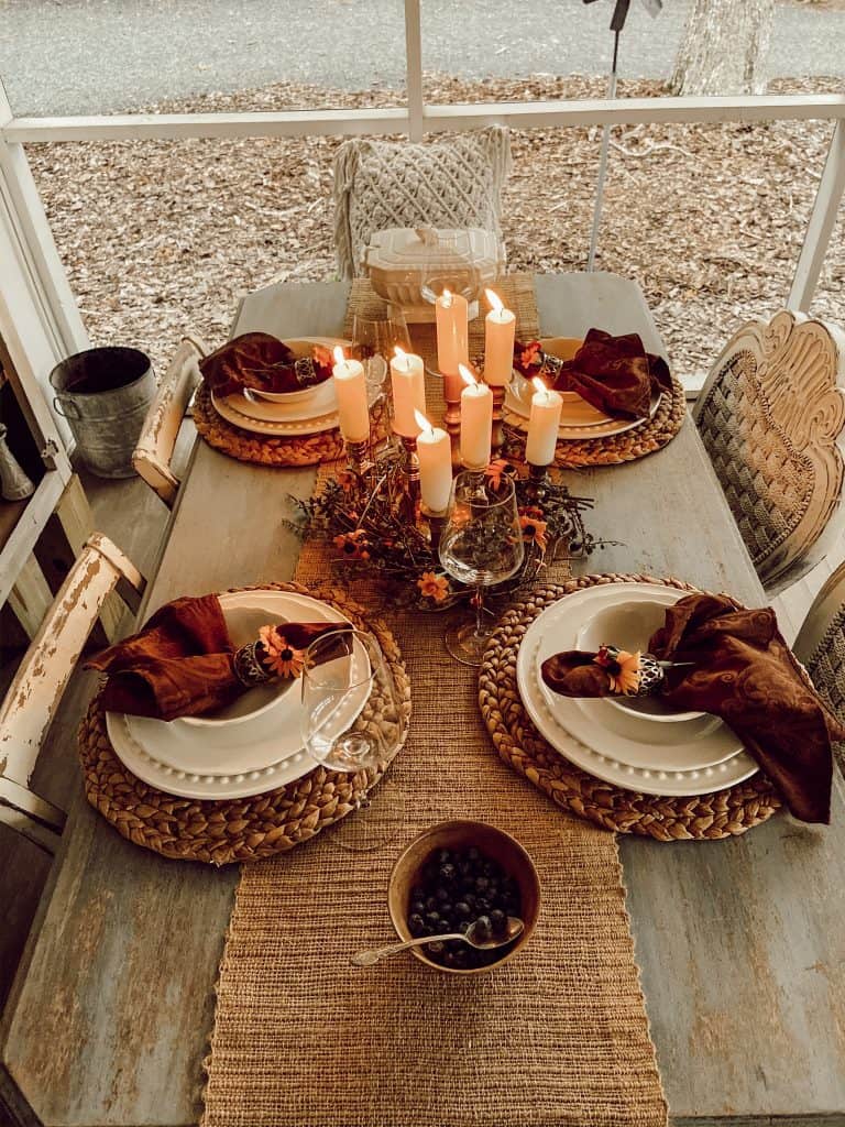 Candles in vintage brass candlesticks surrounded by a bittersweet wreath for a fall table centerpiece.  