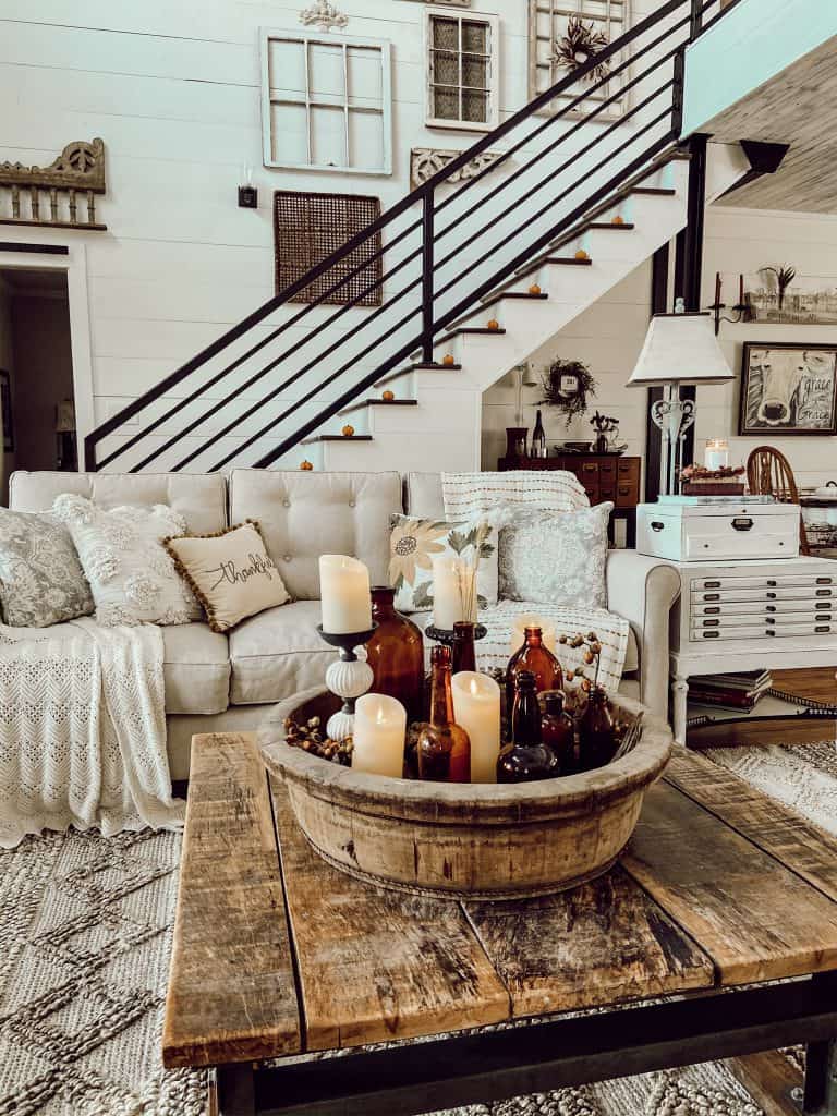 Wooden bowl with amber bottles and flicker candles on coffee table for Fall Table Decor ideas.  