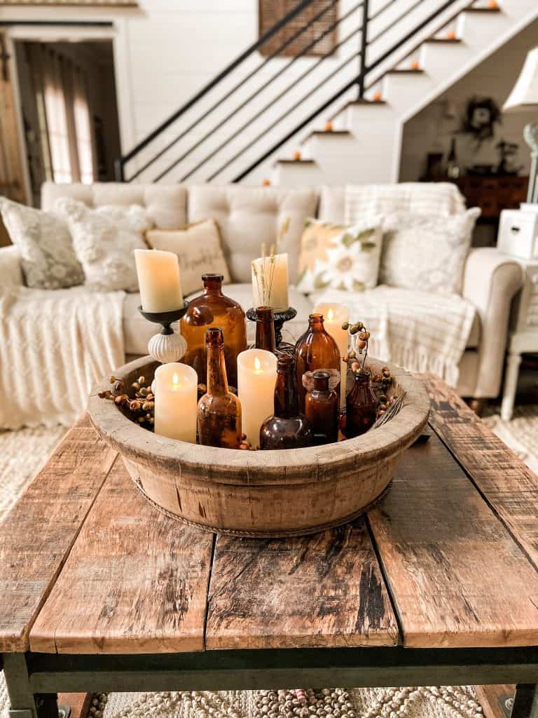 Amber bottle fill the wooden bowl on the coffee table for fall coffee table decorating.