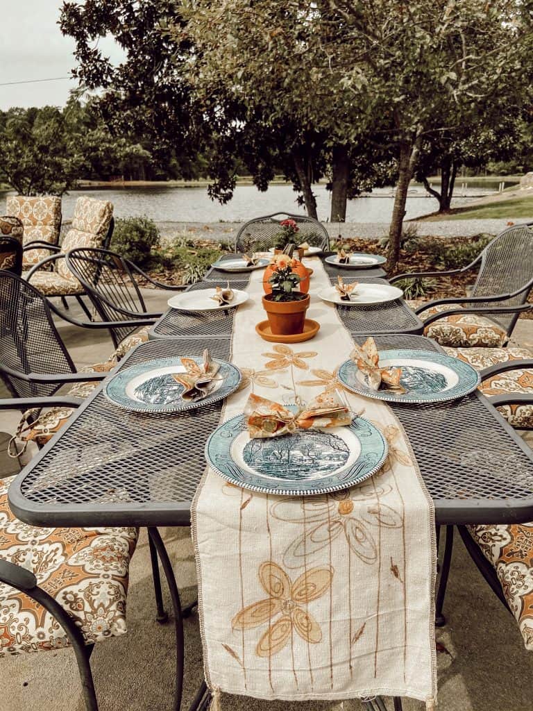 Ideas for outdoor entertaining with mixed matched vintage dishes and clay pots with fresh mums for centerpiece. Dining by water