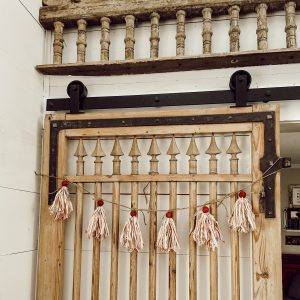 DIY Red and White Ticking Tassel used as a Christmas Garland on the barn door.