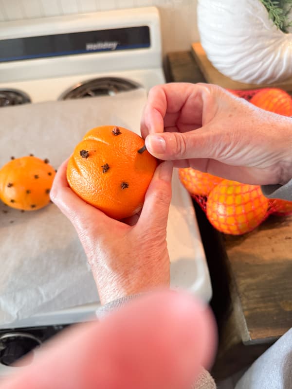 Add whole cloves to oranges