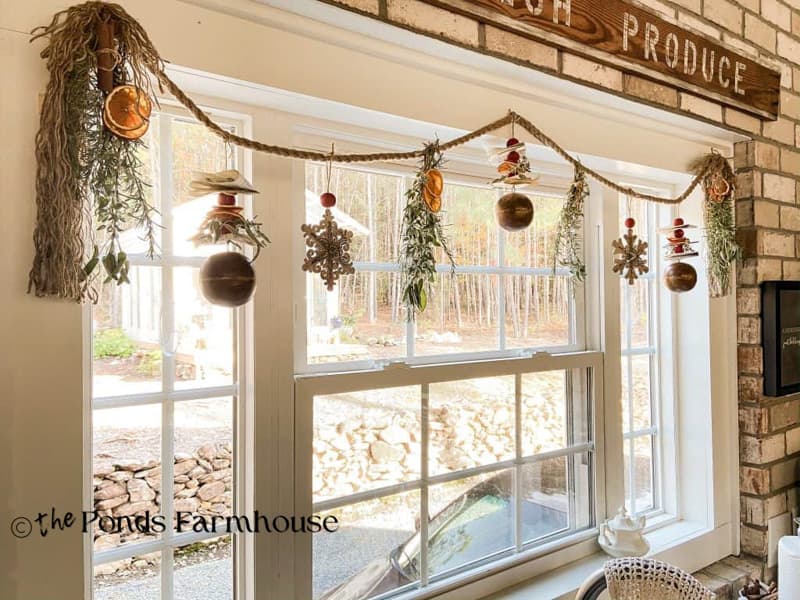 DIY Christmas Garland with dried fruit and herbs hanging in farmhouse kitchen window