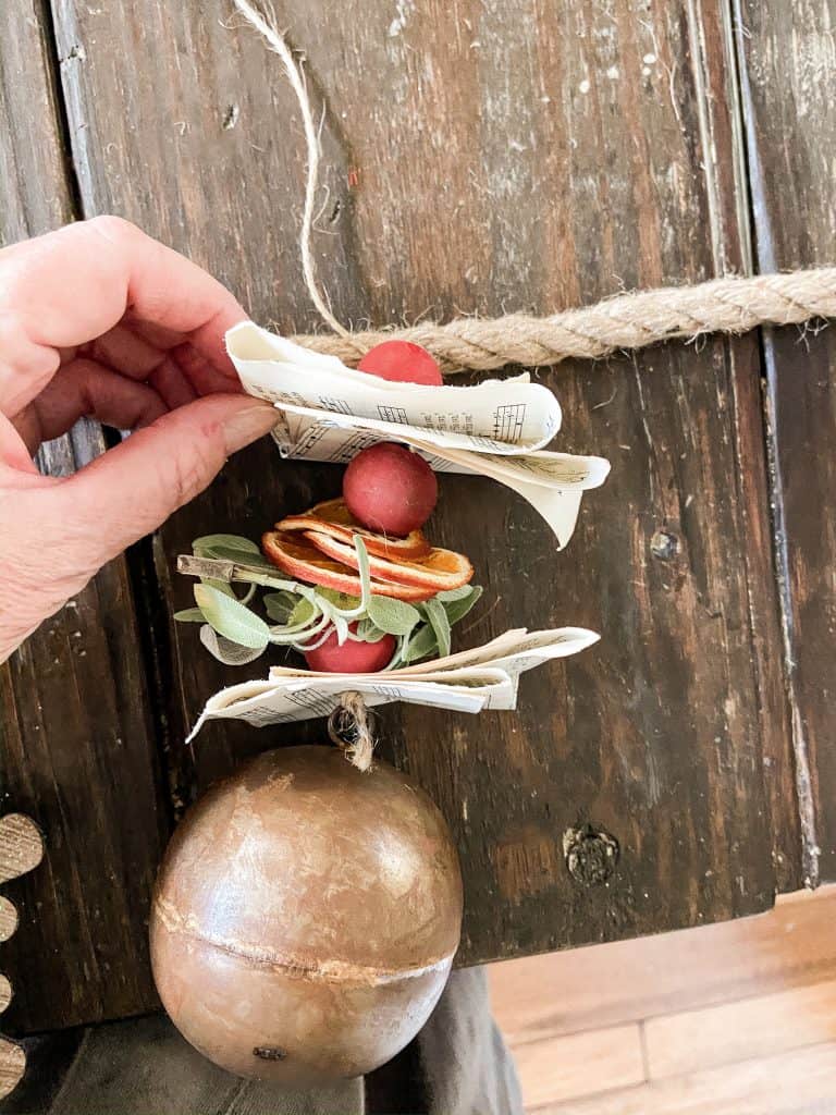 Old music pages, dried fruit, jute twine, fresh herbs and brass Christmas ornament.  