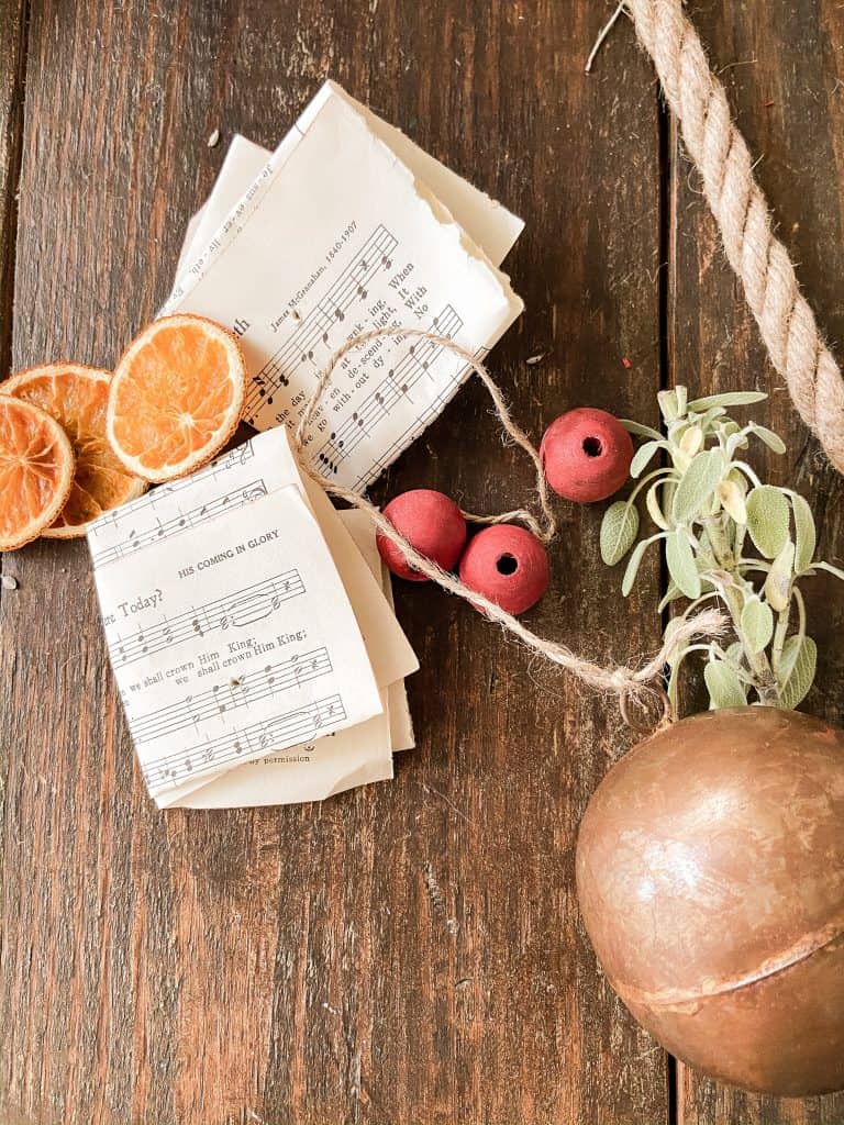 Old music pages, dried fruit, jute twine, fresh herbs and brass Christmas ornament.  
