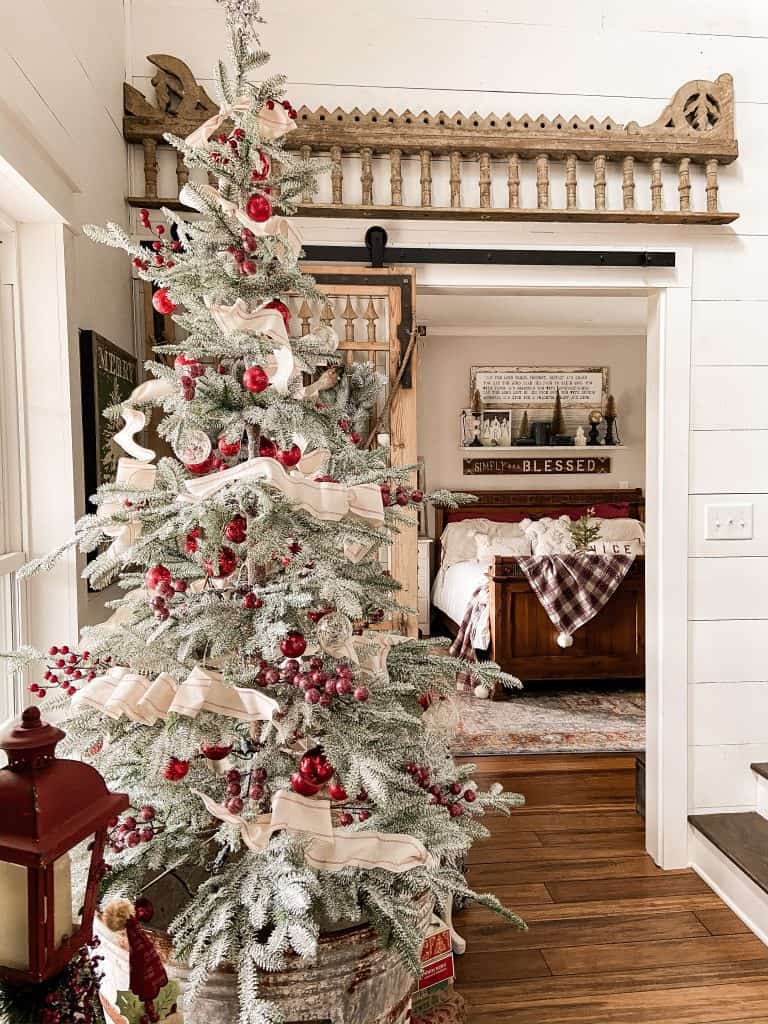 Frost Christmas Tree with red berries and red vintage ornaments at Barn Door and vintage salvage.  Bedroom view with plaid throw.  