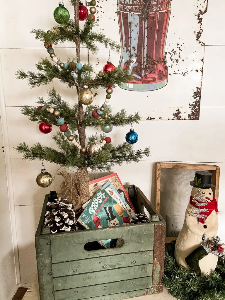 Vintage wood crate filled with vintage Christmas Books and tree filled with vintage ornaments for a Vintage Christmas Decor
