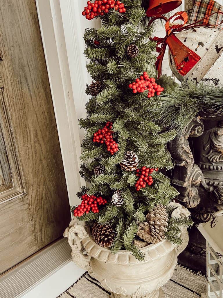 Faux Christmas Tree adorned with berries and foraged pinecones in vintage urn on Front Porch