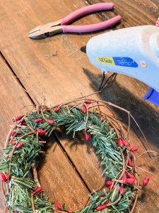 Hot glue mini pinecones to the DIY Christmas Candle Ring made from Dollar Tree supplies.