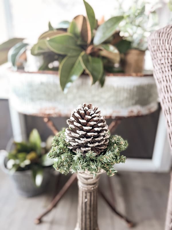 Evergreen candle ring holds a flocked pinecone with DIY fake Snow.