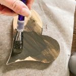 Paint wooden hearts with watery black paint to stain the wood.