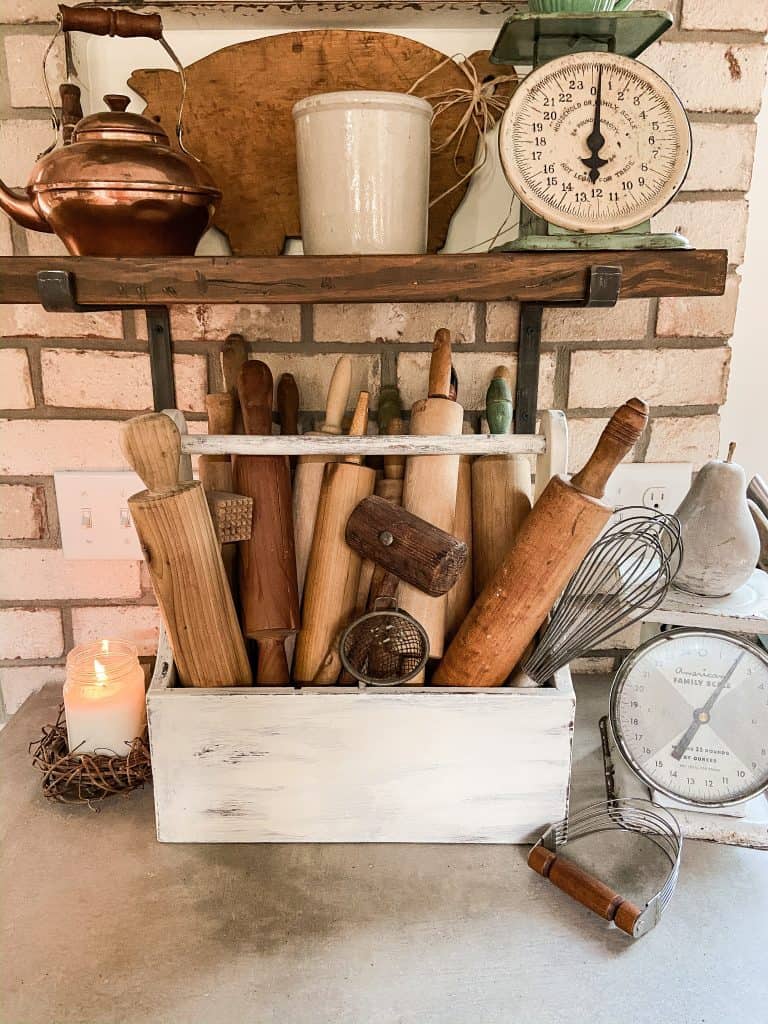 Vintage Tool box filled with old rolling pins creates a charming vignette on kitchen countertop with open shelves.