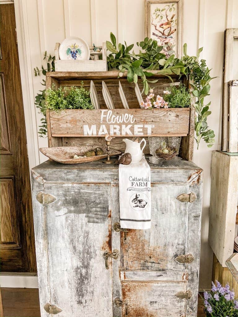 Vintage ice box with antique create with plates and flowers, vintage bread bowl.