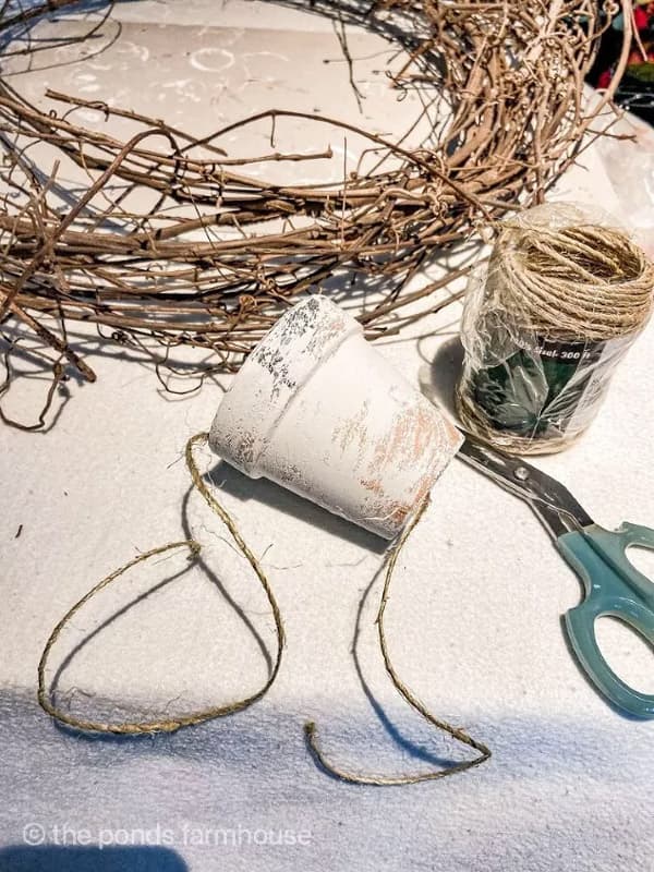 paint clay pots with dry brush of white and tie to wreath with twine