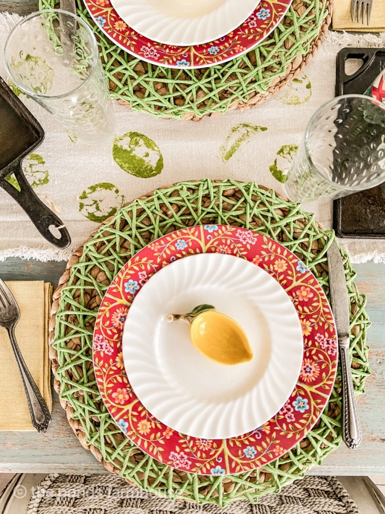 Cinco de mayo table decorations using green placemats with red and flowered plate chargers. Vintage silverware. 