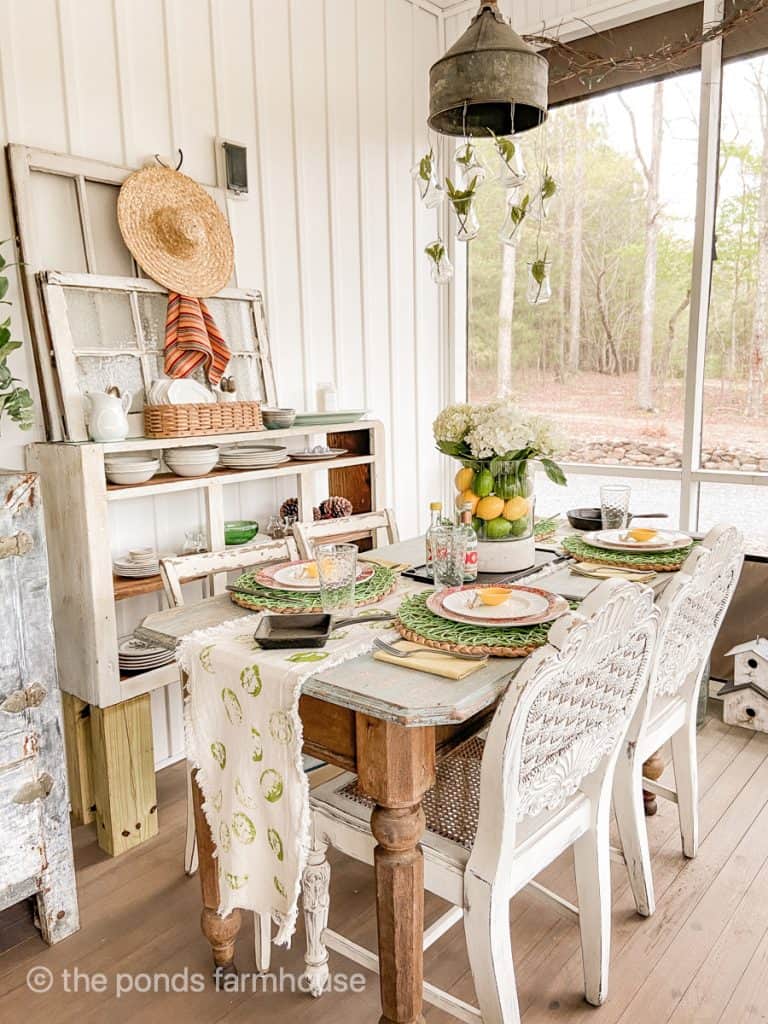 Cinco De Mayo Tablescape, green place mats with red and white plates. Glass vase with lemons, limes and flowers.