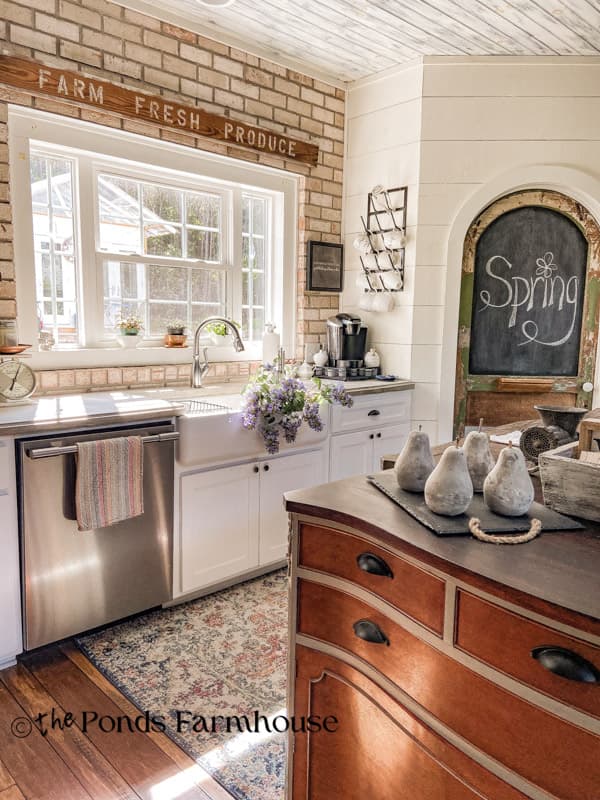 kitchen island with pantry door and farmhouse sink with flowers
