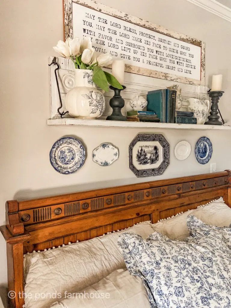 Shelf above bed is repurposed mantel with blue and white vintage dishes and pitchers.  Farmhouse style bedding 