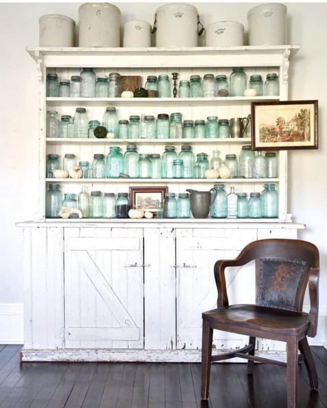 Vintage vintage crocks and mason jars displayed on open hutch
