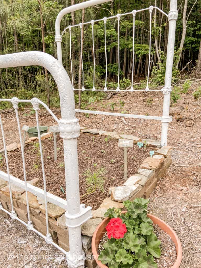 old iron bed made into a raised garden bed for flowers.