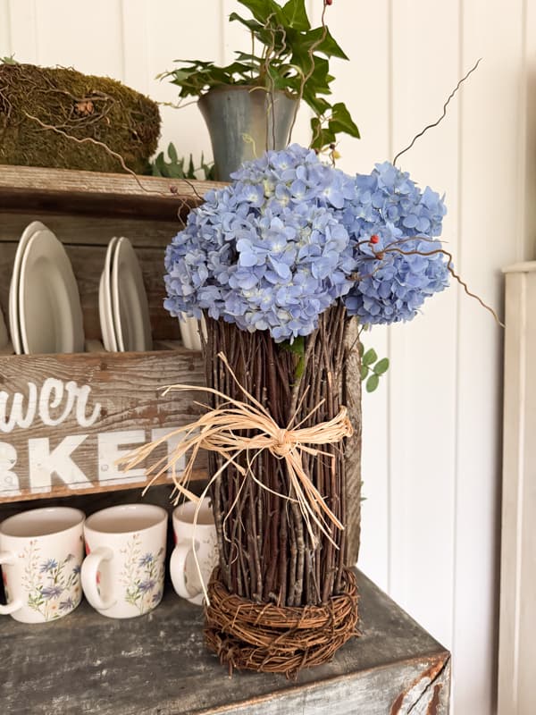 blue hydrangeas in twig vase on porch