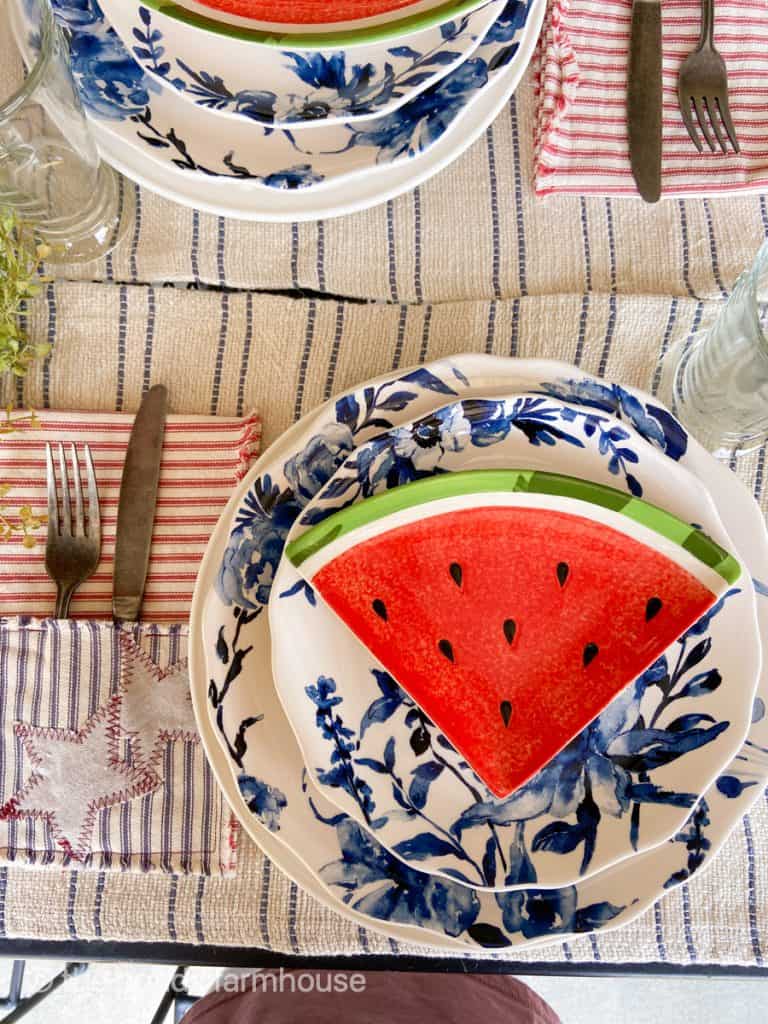 Blue and white dishes on striped placemat.  Watermelon slice plate for a festive Fourth of July Tablescape.