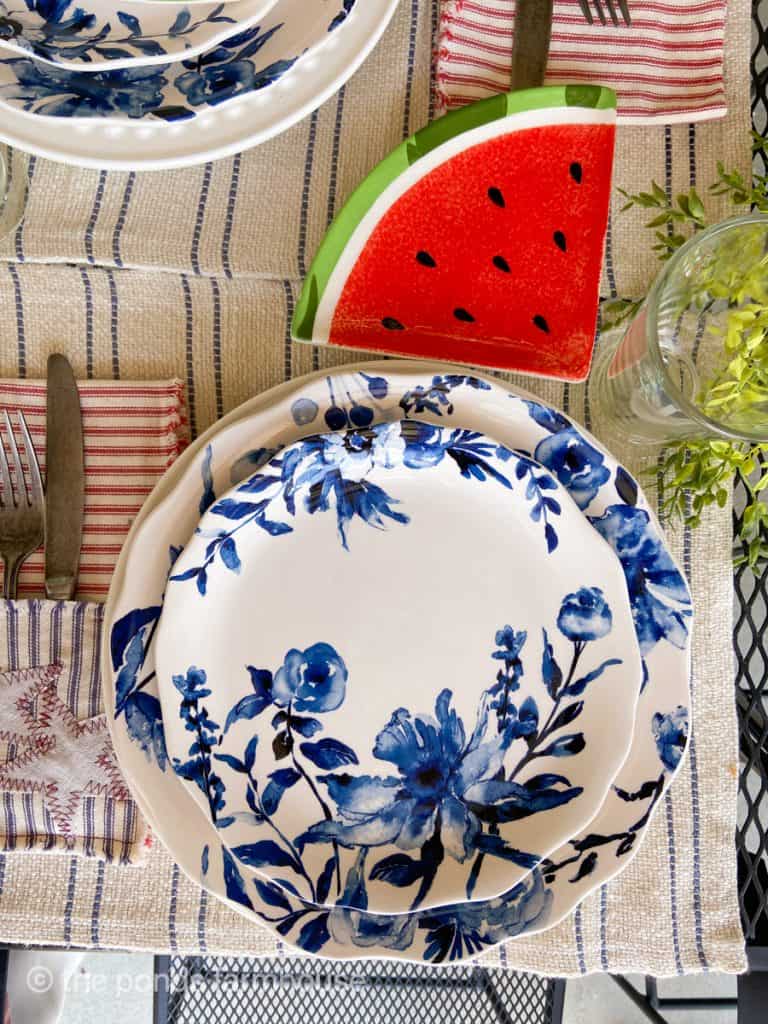 Blue & white dishes on striped placemat.  Watermelon slice plate for a festive Unique Fourth of July Table ideas.