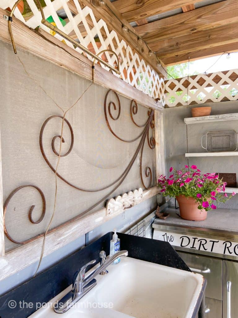 Old screen door hangs above the vintage sink as architectural art in the outdoor kitchen vintage decor.
