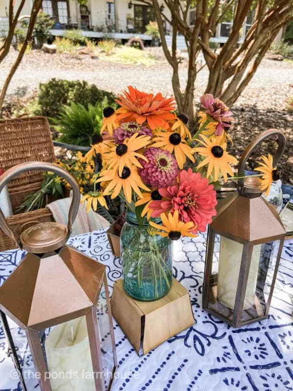 Garden flowers in mason jar with lanterns for picnic table centerpiece