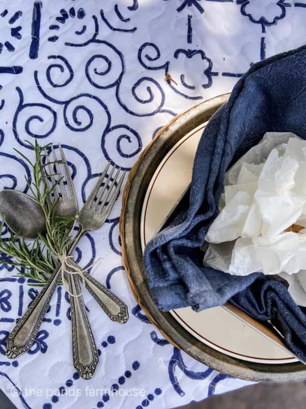 Picnic table place setting with rosemary & jute twine around cutlery